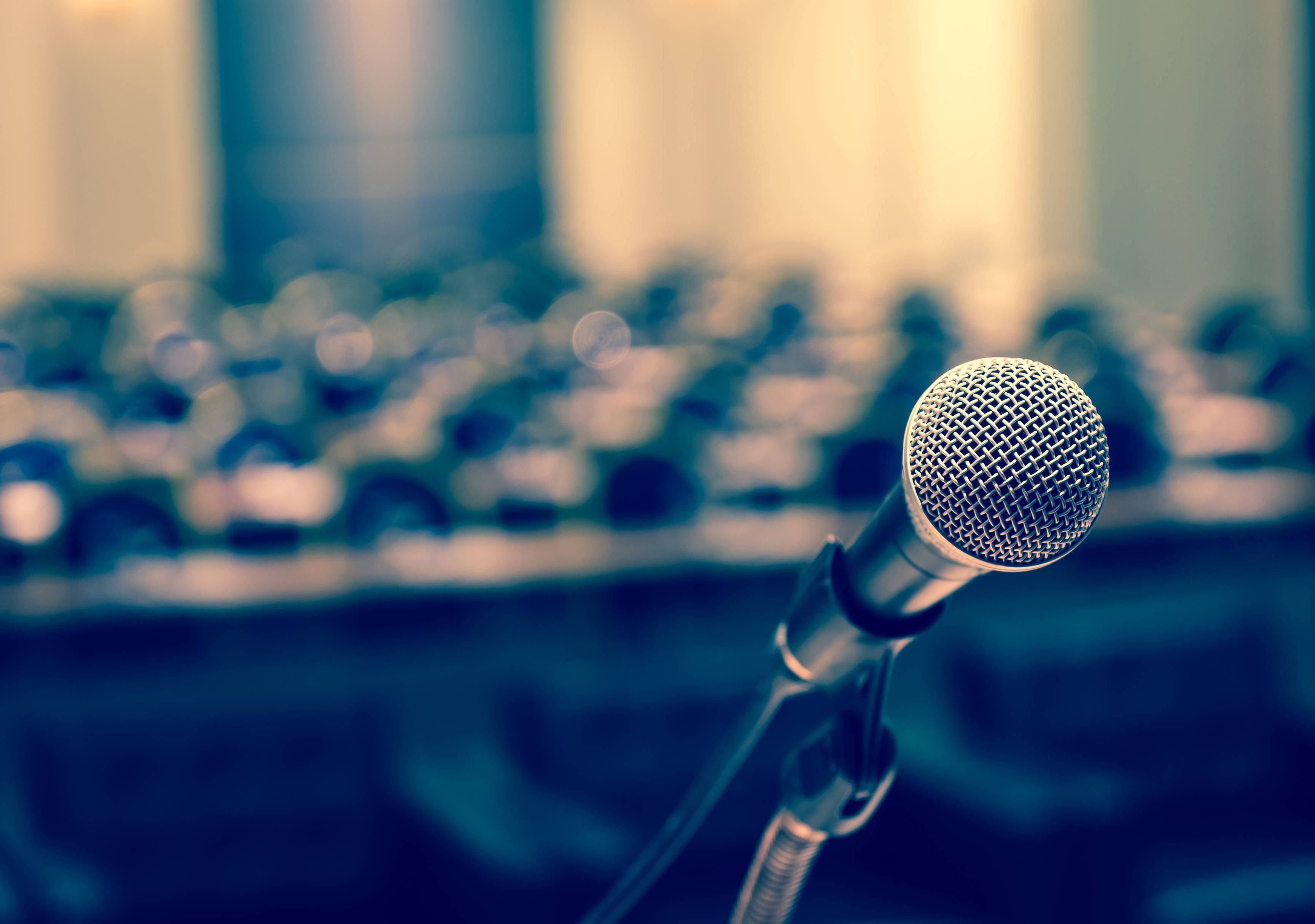 Microphone over the Abstract blurred photo of conference hall or seminar room background