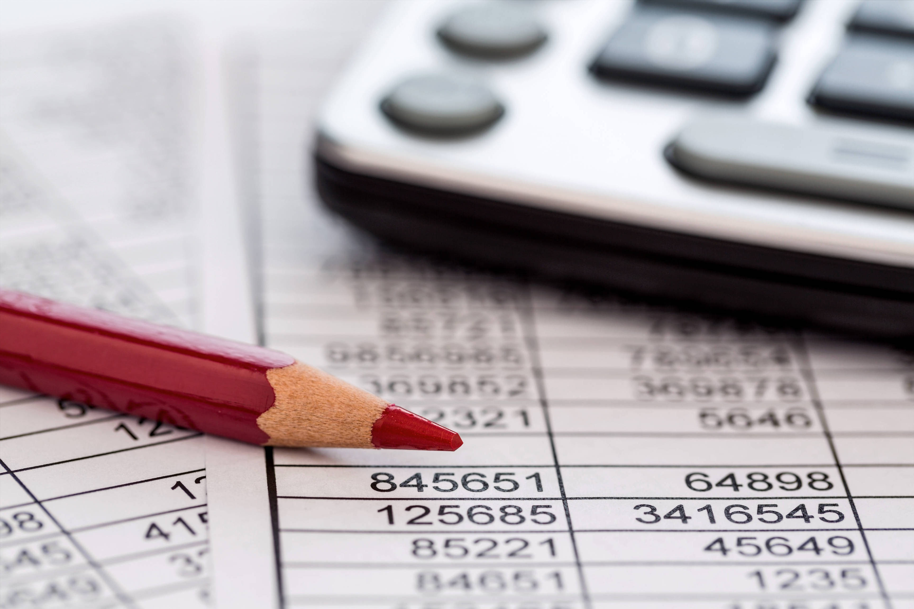a calculator is on a balance sheet numbers are statistics. photo icon for sales, profits and costs.